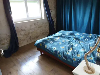 a bedroom with a bed with a blue comforter and a window at Roquevaquiere - Ancienne Grange rénovée - Logement autonome in Ouveillan
