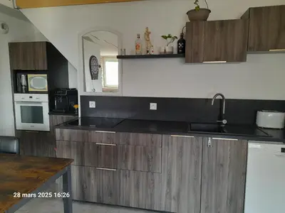 a large kitchen with wooden cabinets and a sink at Roquevaquiere - Ancienne Grange rénovée - Logement autonome in Ouveillan