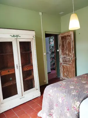 a bedroom with a bed and a dresser and an open door at La 21 avenue des Corbières in Durban-Corbières