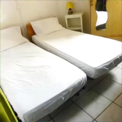 two beds in a room with white sheets at Mimi in Port-la-Nouvelle