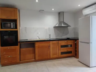 a kitchen with wooden cabinets and a white refrigerator at Charmante maison de village cessenon sur Orb in Cessenon