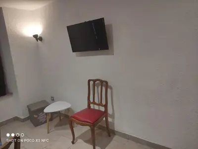 a room with a chair and a tv on a wall at Charmante maison de village cessenon sur Orb in Cessenon