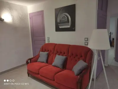 a red couch in a living room with a purple door at Charmante maison de village cessenon sur Orb in Cessenon