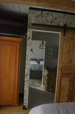 a mirror in a bedroom with a bed and a kitchen at Occit'Homières in Saint-Pons