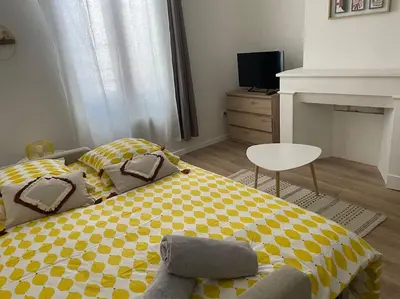 a bedroom with a yellow and white bed and a chair at L'entre Stud' in Castres