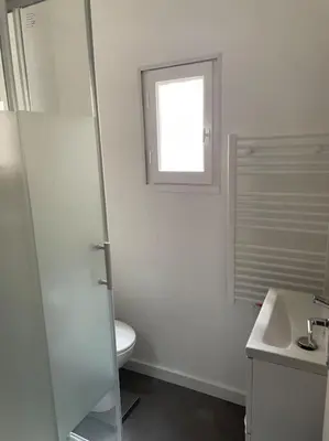 a white bathroom with a toilet and a window at L'entre Stud' in Castres