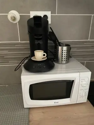 a microwave with a coffee maker and a cup on it at L'entre Stud' in Castres