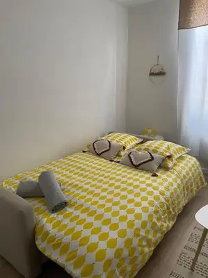 a bedroom with a bed with a yellow and white comforter at L'entre Stud' in Castres