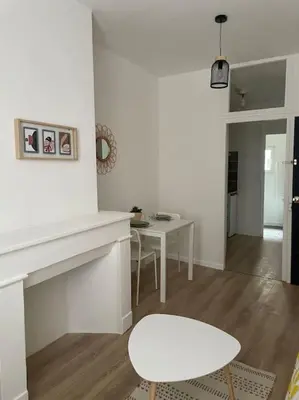 a living room with a table and a white fireplace at L'entre Stud' in Castres