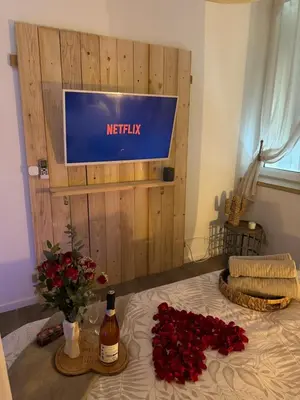 a bed with red roses and a sign on a wall at l'Idylle - Coeur de Bastide - balnéo - Clim in Carcassonne