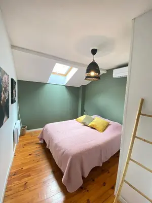 a bedroom with a bed with pink sheets and yellow pillows at Maison de l'Ancienne Porte Neuve in Narbonne