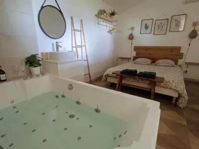 a bath tub with two bottles of wine on a counter at Dépendance avec balnéothérapie in Maurens