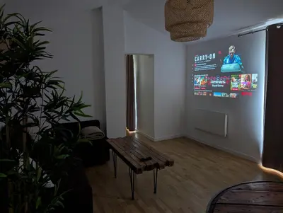 a living room with a table and a large screen at Dépendance avec balnéothérapie in Maurens