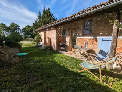 a backyard of a house with a picnic table and a grill at Dépendance avec balnéothérapie in Maurens