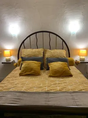 a bed with yellow pillows and two lamps at La Coumereille in Belcaire