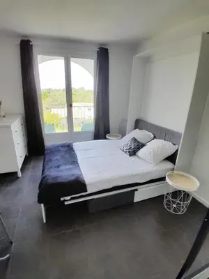 a bedroom with a bed and a large window at Studio Balcon Narbonne Centre in Narbonne
