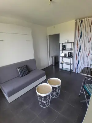 a living room with a couch and two tables at Studio Balcon Narbonne Centre in Narbonne