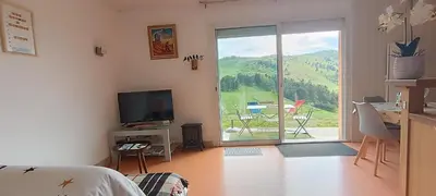 a living room with a television and a sliding glass door at Vue exceptionnelle tout en haut des montagnes, dépaysement total ! in Camurac