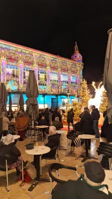 a group of people sitting at tables in front of a building at Hébergements Narbonne centre - Local vélos et motos in Narbonne