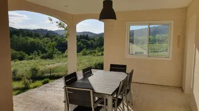a wooden table and chairs on a patio with a window at Le Gîte de Berignac in Antugnac
