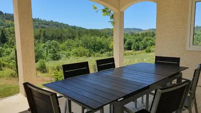 a table and chairs on a porch with a view at Le Gîte de Berignac in Antugnac
