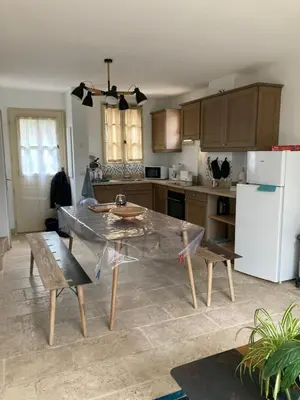 a kitchen with a table and chairs and a refrigerator at Saint laurent de la cabrerisse Rivière proche Lagrasse in Saint-Laurent-de-la-Cabrerisse