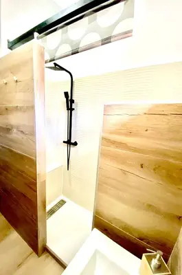 a glass shower in a bathroom with a wooden wall at La pinéa in Port-la-Nouvelle