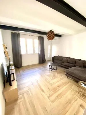 a living room with a couch and a wooden floor at La pinéa in Port-la-Nouvelle