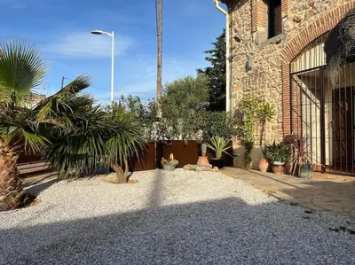 a courtyard with potted plants in front of a building at Maison Bacchus, gîte insolite dans cuve à vin in Caves