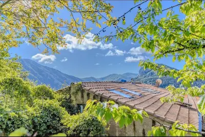an old house with a tile roof with mountains in the background at Secluded home in Le Caunil in Salvezines