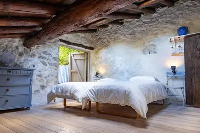 a bedroom with a large bed in a stone wall at Secluded home in Le Caunil in Salvezines
