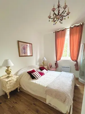 a bedroom with a bed with red curtains and a chandelier at Château Mesdames in Labastide-Rouairoux