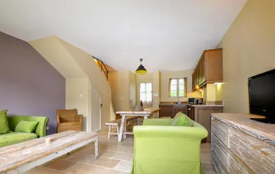 a living room with green furniture and a kitchen at 2 Bedroom Awesome Home In Saint-Laurent-De-La-Ca in Saint-Laurent-de-la-Cabrerisse