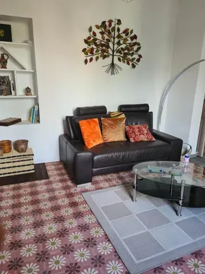 a living room with a leather couch and a glass table at Appartement rénové avec jardin in Cuxac-dʼAude
