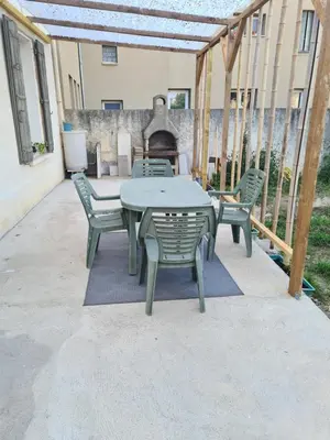 a patio with a table and chairs and a fireplace at Appartement rénové avec jardin in Cuxac-dʼAude