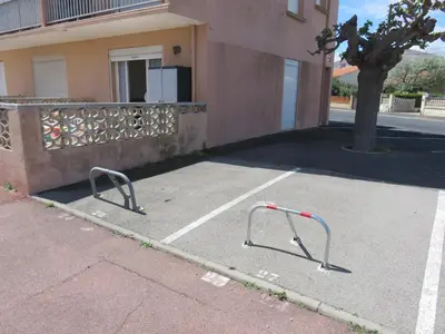 a parking lot with two bars in front of a building at Le Géranium in Port-la-Nouvelle