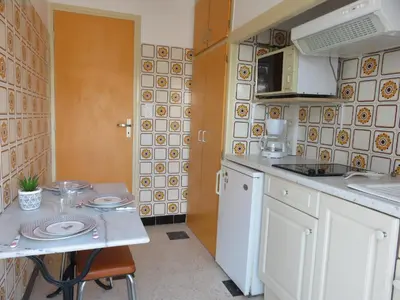 a small kitchen with a table and a microwave at Le Géranium in Port-la-Nouvelle