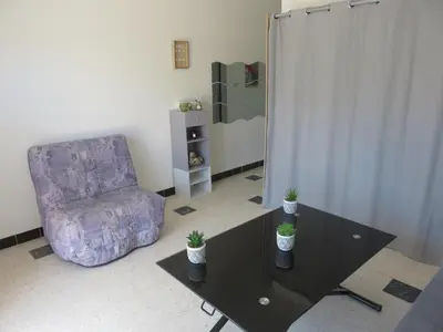 a living room with a couch and a table and a chair at Le Géranium in Port-la-Nouvelle