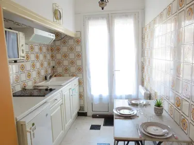 a kitchen with white cabinets and a table and a window at Le Géranium in Port-la-Nouvelle