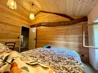 a bedroom with a bed in a wooden room at Parenthèse en Forêt - Gîte Baliveau, Sidobre in Le Bez