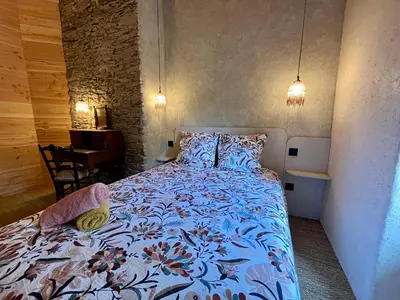 a bedroom with a bed with a blue comforter at Parenthèse en Forêt - Gîte Baliveau, Sidobre in Le Bez