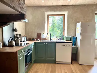 a kitchen with green cabinets and a white refrigerator at Parenthèse en Forêt - Gîte Baliveau, Sidobre in Le Bez