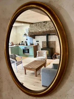 a mirror reflecting a living room with a couch and a table at Parenthèse en Forêt - Gîte Baliveau, Sidobre in Le Bez