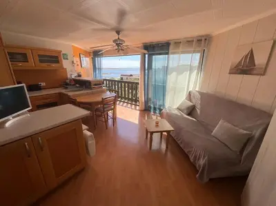 a living room with a couch and a table and a kitchen at Studio vue mer et plage in Gruissan