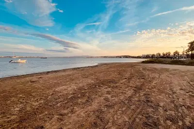a sandy beach with a boat in the water at Studio vue mer et plage in Gruissan