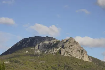a mountain in front of a blue sky with clouds at Roulotte in Bugarach
