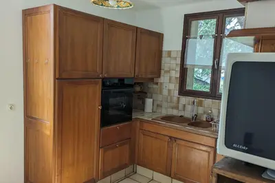 a kitchen with wooden cabinets and a television at La Pinède in Espéraza