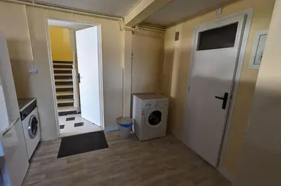 a laundry room with a washing machine and a door at La Pinède in Espéraza