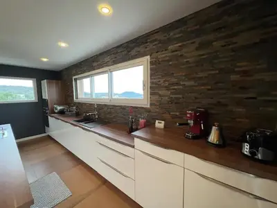 a kitchen with white cabinets and a brick wall at Villa contemporaine avec piscine in Montredon