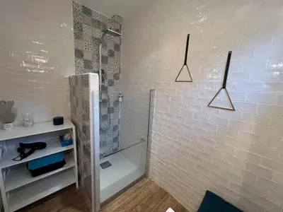 a bathroom with a shower and a white tiled wall at Villa contemporaine avec piscine in Montredon
